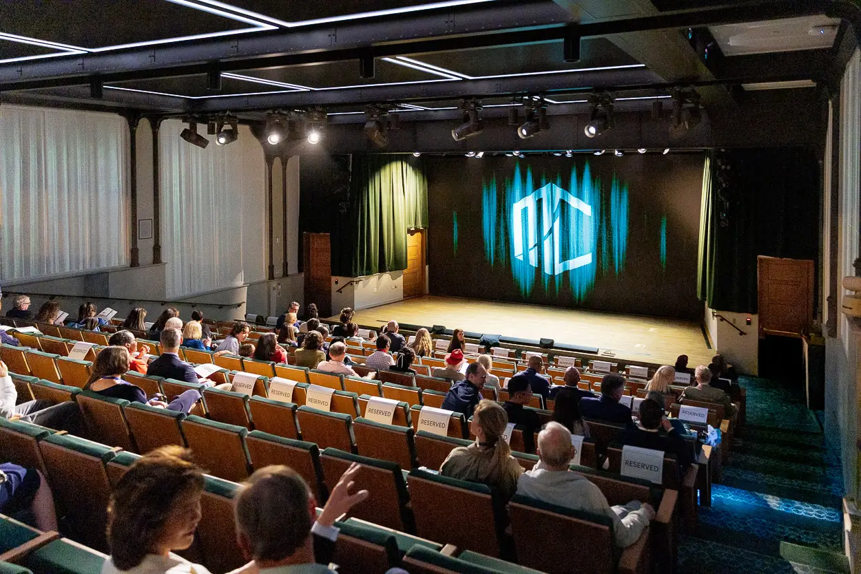 Keynote session in a Washington DC auditorium with speaker, audience seating, and clean corporate event lighting