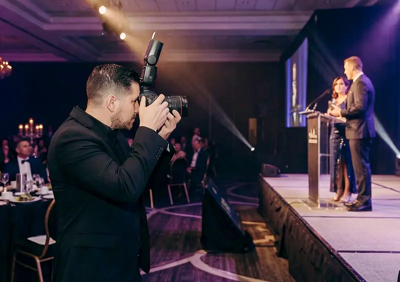 Luis Rivas photographing corporate event speakers on stage during a formal Washington DC gala program