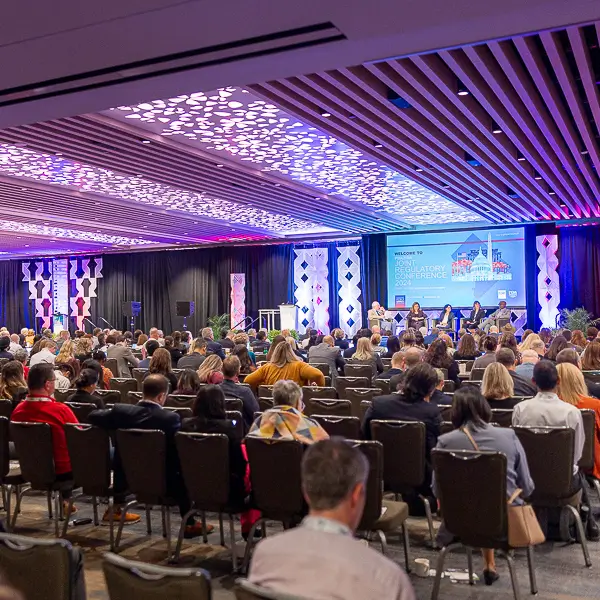 Keynote speaker presenting during a conference summit in Washington DC with professional stage lighting and audience