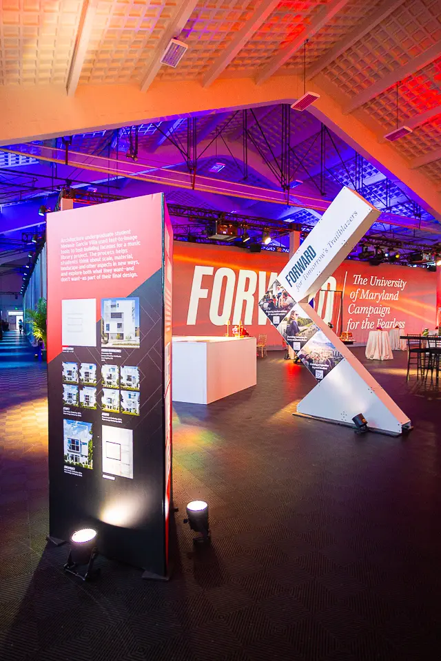 University of Maryland Forward campaign signage and portrait display under red and blue event lighting
