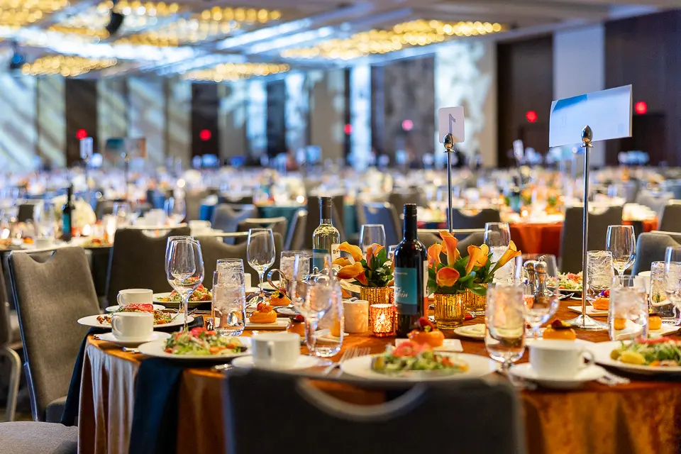 Formal dinner table details with the Herb Wegner Awards 2026 stage and ballroom in the background.