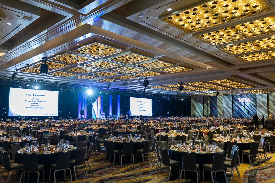 Wide view of the Herb Wegner Awards 2026 ballroom with a lit stage, presentation screens, and dinner seating.