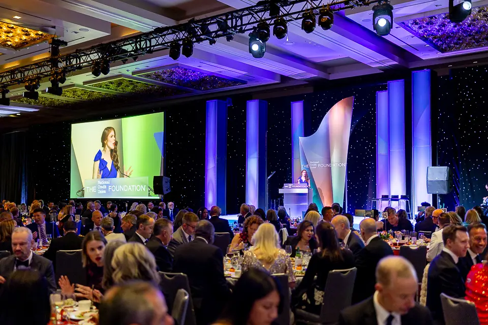 Speaker at the Herb Wegner Awards 2026 podium with dinner guests watching from round tables.